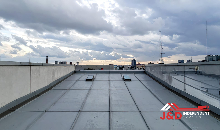 Commercial flat roof membrane installation with standing seams and parapet walls under a cloudy sky, featuring industrial roofing Edmonton services by J&D Independent Roofing.